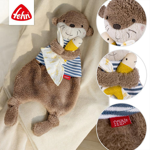 Das Schmusetuch Otter ist ein weiches Plüschtier mit gestreiftem Hemd, das einen gelben Fisch und ein sternförmiges Tuch hält. In der Nahaufnahme ist das Fehn-Logo zu sehen, perfekt für Babys.