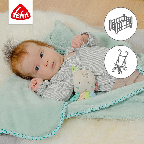Ein Baby liegt auf der mintgrünen Kuscheldecke Oktopus und hält ein Plüschtier in der Hand; Krippen- und Kinderwagensymbole unterstreichen seine Vielseitigkeit. Fehn-Logo oben links - ideal als Baby-Geschenk.