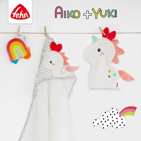 An einer Wäscheleine hängen drei Baby-Badeartikel mit Einhornmotiven: ein Kapuzenbadetuch Einhorn, ein Waschhandschuh und ein Plüsch-Regenbogentier. Zu sehen sind Aiko + Yuki und das Fehn-Logo.