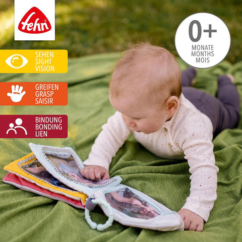 Ein Baby auf einer grünen Decke erkundet das Fotoalbum Loopy & Lotta im Freien. Informative Grafiken zeigen, dass es das Sehen, Greifen und die Bindung fördert - ein ideales Geburtstagsgeschenk für 0+ Monate mit seinem Nilpferd- und Giraffen-Design.