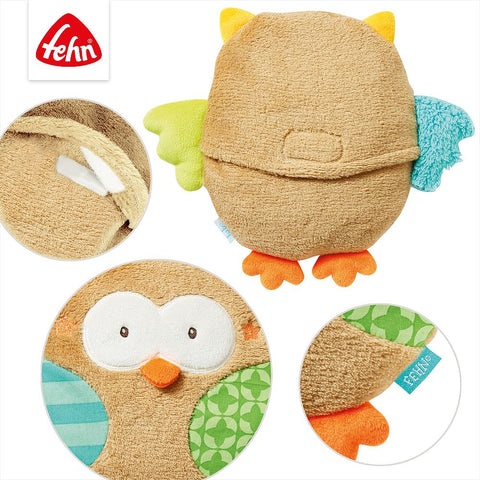 Die Wärmekissen Eule ist eine Plüsch-Eule mit bunten Flügeln und Füßen, die aus verschiedenen Blickwinkeln gezeigt wird. Sie hat eine kleine Vordertasche für ein Wärme-/Kältesäckchen und trägt das Fehn-Markenschild.
