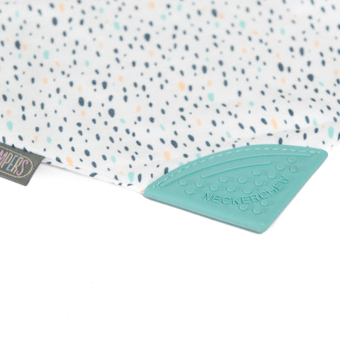 Nahaufnahme des Neckerchew Zahnen Dribble Lätzchen - birnenförmige Tropfen, mit einem mehrfarbig gepunkteten Stoff, einem tealfarbenen, strukturierten Silikonbeißring mit der Aufschrift NECKERCHIEF an der Ecke und einem sichtbaren Markenetikett - perfekt als stylisches Neckerchew oder Zahnlätzchen.