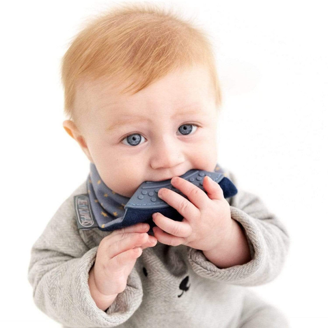 Ein Baby mit hellem Haar und blauen Augen kaut auf dem Neckerchew Zahnen Dribble Lätzchen - Midnight Stars, während es ein graues Outfit vor einem weißen Hintergrund trägt - ein perfektes Babygeschenk.