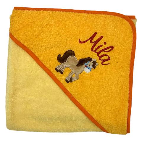 Das Kapuzenbadetuch Hellgelb/Gold 100x100cm hat eine orangefarbene Bordüre, eine Pferdestickerei und "Mila" in Rot an einer Ecke. Aus weicher Baumwolle gefertigt, ist es perfekt für Kinder.