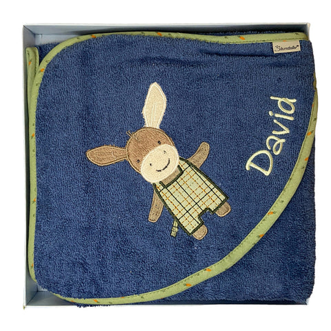 Das Kapuzenbadetuch Esel Emmilius in Mittelblau (100x100cm) hat eine grüne Bordüre, eine niedliche Esel-Stickerei, den Namen David in Weiß und ist aus weicher Bio-Baumwolle gefertigt. Wird gefaltet in einer Schachtel geliefert - perfekt für Babys.