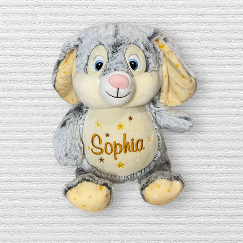 Clovis Brampton III, der Cubbies Hase, ein grau-cremefarbenes Plüschtier mit blauen Augen und gelben Sternmustern, sitzt auf weißem Untergrund; "Sophia" ist auf dem Bauch gestickt - ein süßes Geschenk.