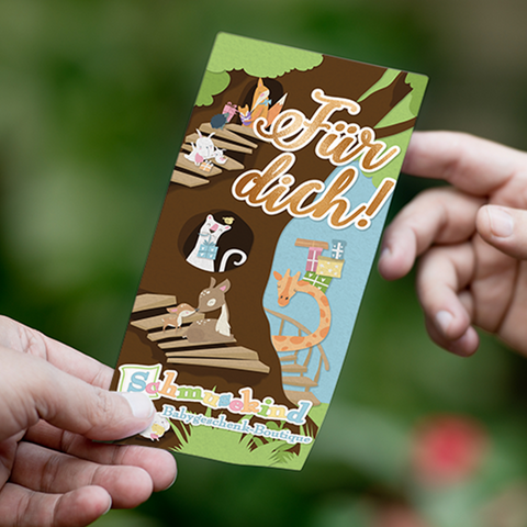 Eine Hand hält eine bunte Karte mit Cartoon-Tieren, Holzstegen und dem Text "Für dich!" - der Physischer Schmusekind Gutschein (per Post verschickt), ideal als Geschenk für werdende Eltern aus der Sahnestückkind Babygeschenke Boutique.