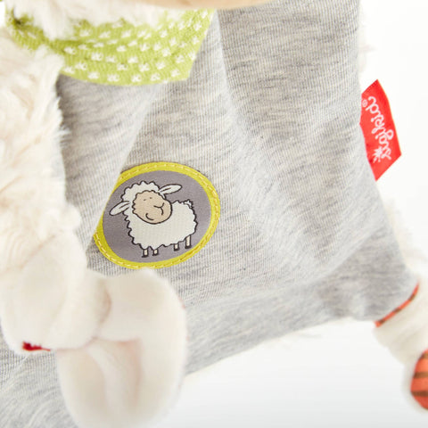 Nahaufnahme eines grauen Stoffes mit dem Schnuffeltuch Schaf, Boller Schäfle mit Cartoon-Schaf-Aufnäher und rotem Steiff-Anhänger - ein ideales Plüschtier für Komfort und emotionale Entwicklung.