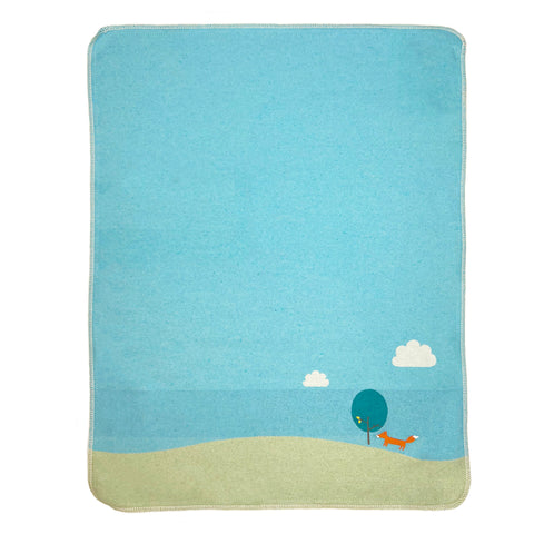 Die JUWEL Decke Fuchs mit Stickerei 70x90cm ist eine rechteckige Decke aus Baumwollflanell mit einem minimalistischen Design, das einen blauen Himmel, weiße Wolken, einen grünen Hügel, einen Baum und einen orangefarbenen Fuchs in der unteren Ecke zeigt.