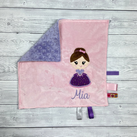 Rosa Schmusedecke mit dunkelhaariger Prinzessin im lilafarbenen Kleid und dem Namen ‚Mia‘, mit lila Rückseite und bunten Satinbändern.