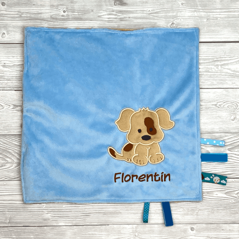 Blaue Kuscheldecke mit Hundemotiv und Name ‚Florentin‘, blaue und dunkelgrüne Stoffbändchen an der Seite.