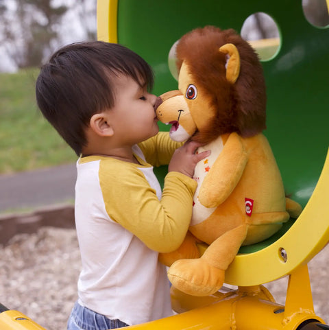 Ein kleines Kind in einem gelb-weißen Hemd berührt die Nasen von Numbutu, dem Löwe, auf dem Spielplatz und genießt möglicherweise ein einzigartiges Geburtstagsgeschenk.