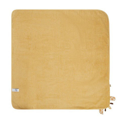 Eine quadratische, senfgelbe Babydecke "Giraffe Kaya Sand" (100x100cm) aus weicher Baumwolle, mit einem kleinen weißen Etikett und ein paar Stoffanhängern an einer Kante, liegt flach auf einem weißen Hintergrund.