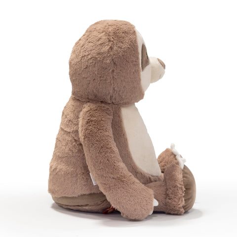 Ein braunes und beiges "Clingy, das Faultier" Plüschtier sitzt aufrecht mit dem Gesicht nach rechts auf einem schlichten weißen Hintergrund - ein einzigartiges Geschenk für jede Gelegenheit.